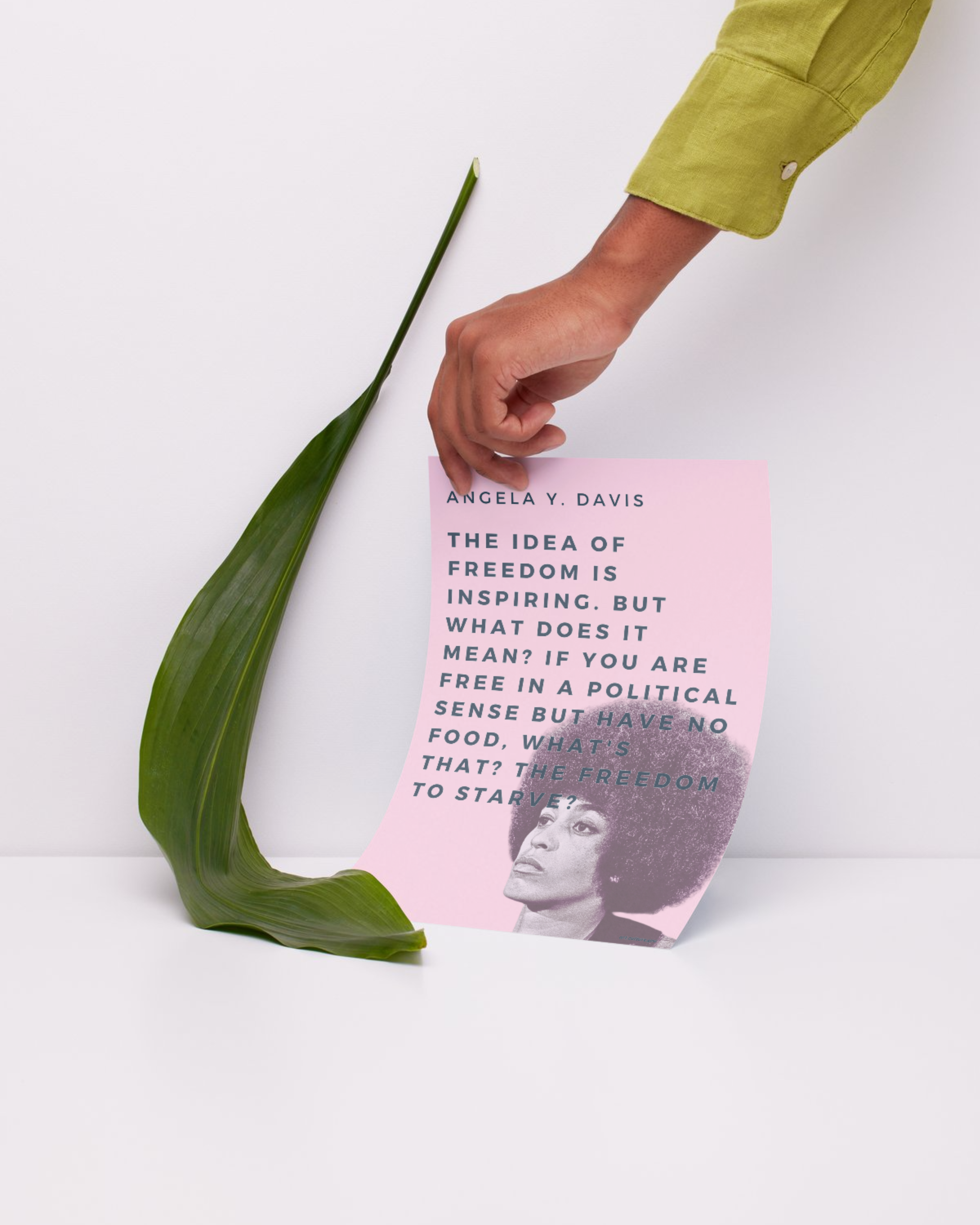 a hand holding a poster against a wall. the poster has angela y davis' photo and her quote.